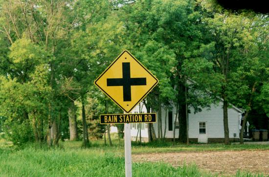 183.jpg - Cross road sign at Kenosha County Highway H & Bain Station Road in May 2010.  Bain became a station in 1906 when the New Line was built, crossing the KD at that point.